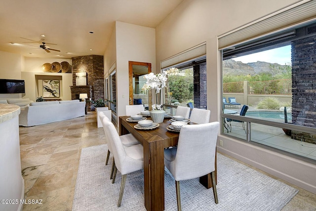 dining area with a mountain view, recessed lighting, a ceiling fan, stone finish floor, and a high ceiling