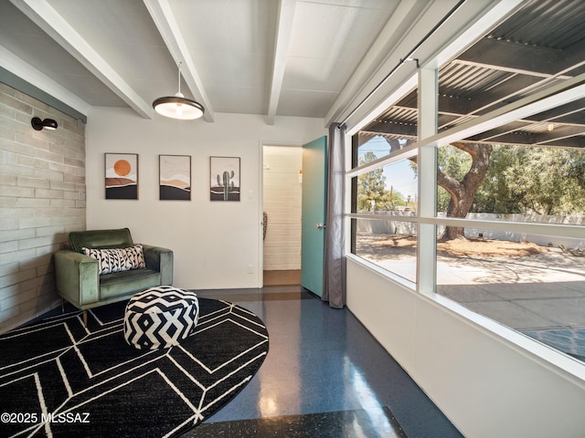 interior space featuring speckled floor, baseboards, and beam ceiling