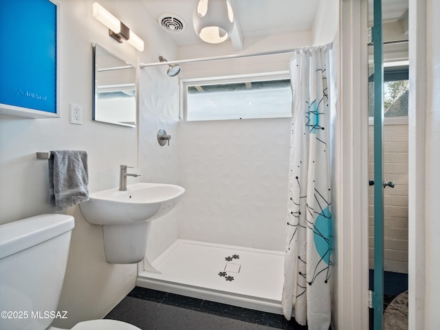 bathroom with toilet, visible vents, and a stall shower