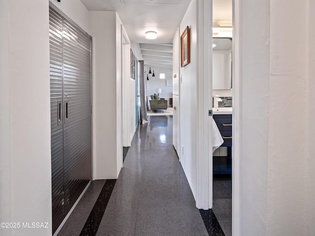 hall featuring baseboards and dark speckled floor