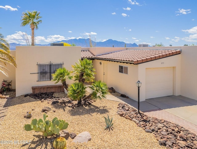 view of front of property featuring concrete driveway, a tiled roof, a mountain view, a garage, and stucco siding