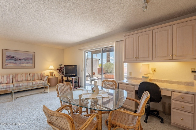 dining space featuring built in desk, a textured ceiling, and light carpet