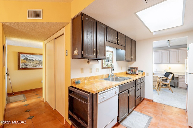 kitchen featuring light countertops, visible vents, a sink, light tile patterned flooring, and white appliances