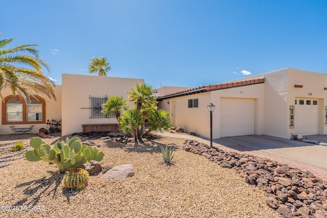 view of front facade with a garage, driveway, and stucco siding