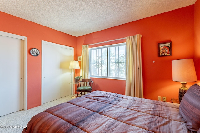 carpeted bedroom with multiple closets and a textured ceiling