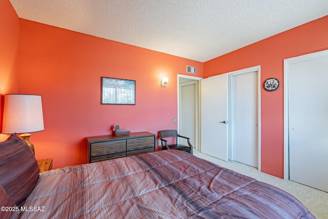 bedroom featuring visible vents, carpet, and a textured ceiling