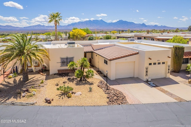 view of front of house with stucco siding, an attached garage, a tile roof, driveway, and a mountain view