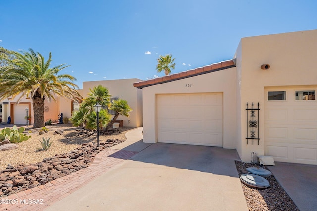 view of front of house with a tiled roof, driveway, and stucco siding