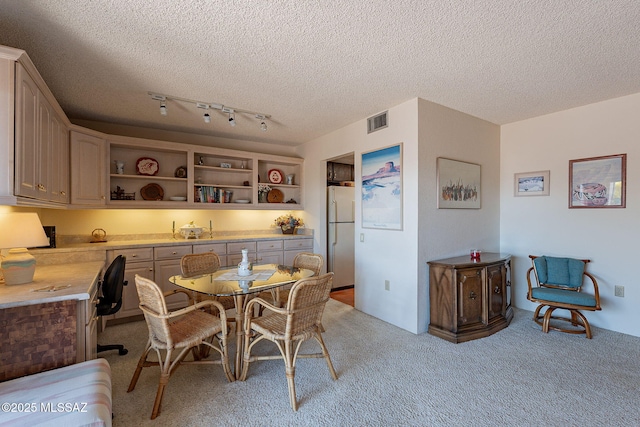 dining space featuring visible vents, a textured ceiling, and light colored carpet
