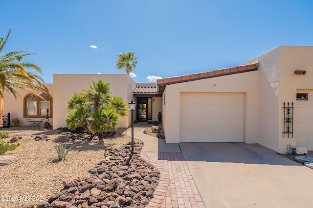 view of front of home with a garage, stucco siding, a tile roof, and concrete driveway