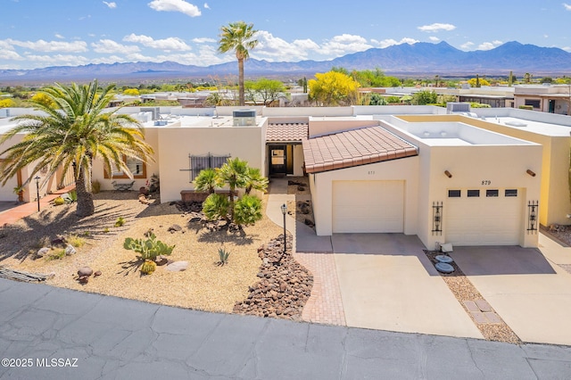 view of front of home with a garage, a tiled roof, a mountain view, and stucco siding