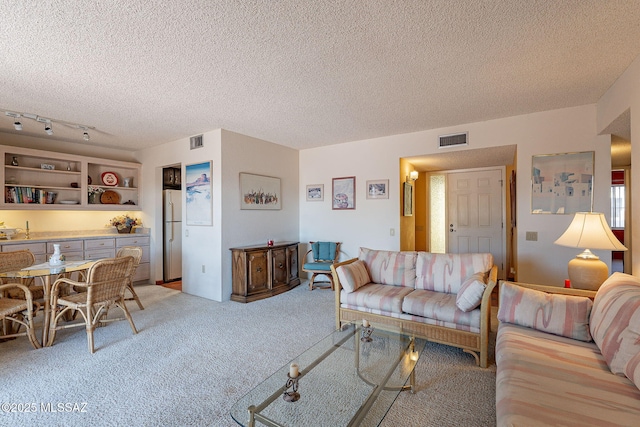 carpeted living area featuring a textured ceiling and visible vents