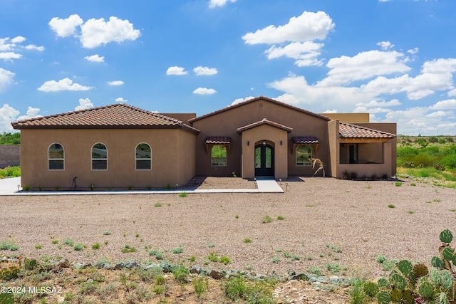 mediterranean / spanish-style home featuring french doors, a tile roof, and stucco siding
