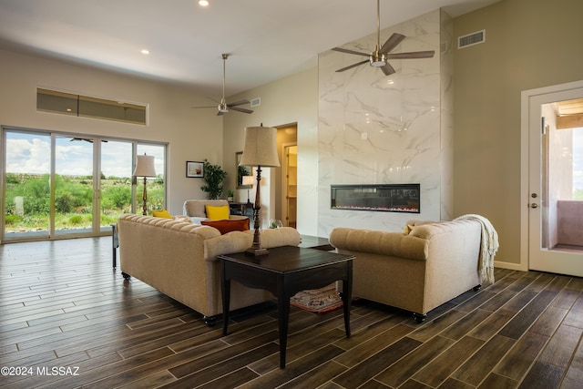living area with high vaulted ceiling, a ceiling fan, dark wood-type flooring, and visible vents