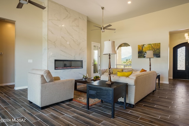 living room with dark wood-style flooring, a ceiling fan, and baseboards