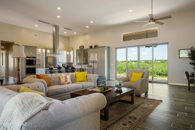 living room featuring baseboards, a towering ceiling, visible vents, and ceiling fan