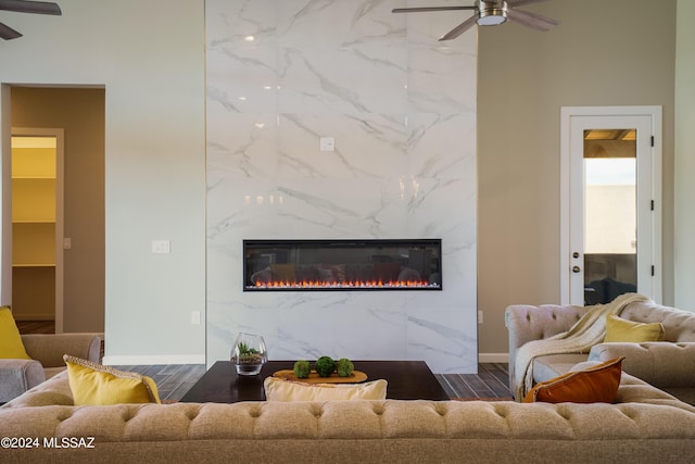 living area with baseboards, ceiling fan, wood finished floors, and a premium fireplace