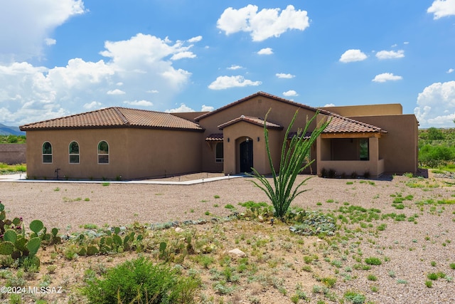 mediterranean / spanish home featuring a tiled roof and stucco siding