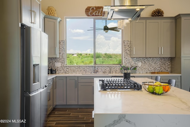 kitchen with tasteful backsplash, gray cabinetry, light stone counters, a sink, and refrigerator with ice dispenser
