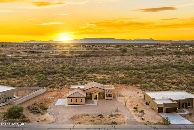 aerial view at dusk featuring a mountain view and view of desert
