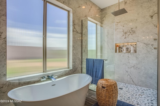 full bathroom with walk in shower, a soaking tub, and wood finished floors