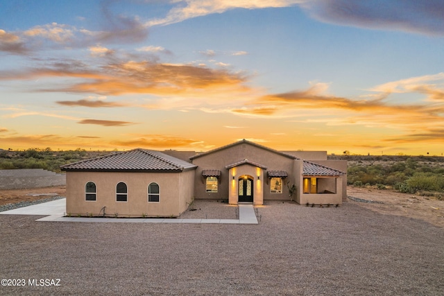mediterranean / spanish home with a tiled roof, french doors, and stucco siding