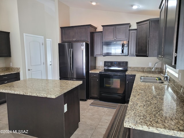 kitchen with light stone countertops, a sink, lofted ceiling, and black appliances