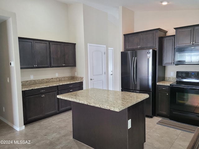 kitchen with high vaulted ceiling, light stone countertops, black appliances, and a kitchen island