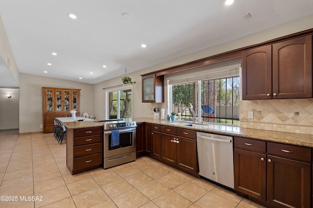 kitchen featuring appliances with stainless steel finishes, a sink, a peninsula, recessed lighting, and tasteful backsplash