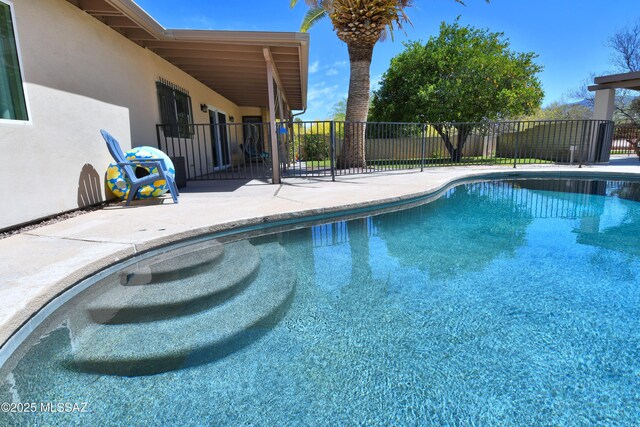 view of swimming pool featuring a patio and fence