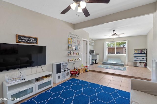 tiled living area featuring ceiling fan, beamed ceiling, and baseboards