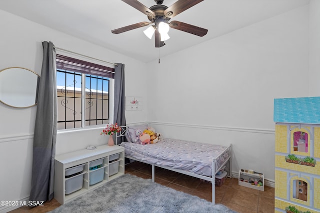 tiled bedroom with ceiling fan and baseboards