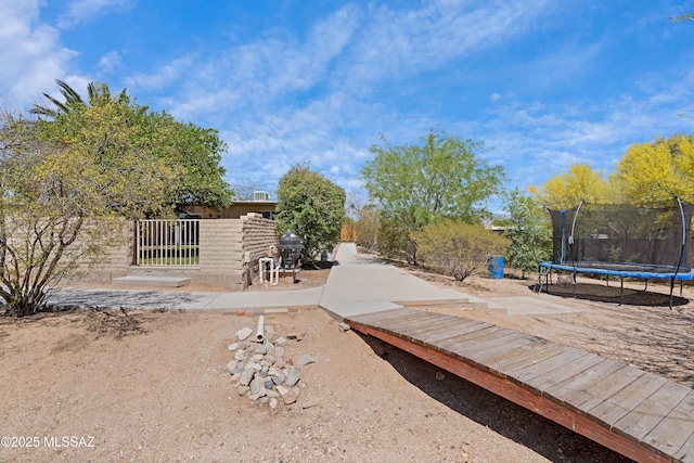 view of yard with a trampoline and fence