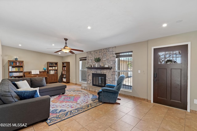 living area with ceiling fan, a stone fireplace, light tile patterned flooring, recessed lighting, and baseboards