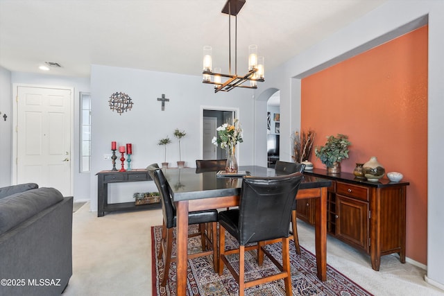7541 W Wandering Coyote Dr, Tucson, AZ 85743 - dining area with light colored carpet, arched walkways, a chandelier, and baseboards