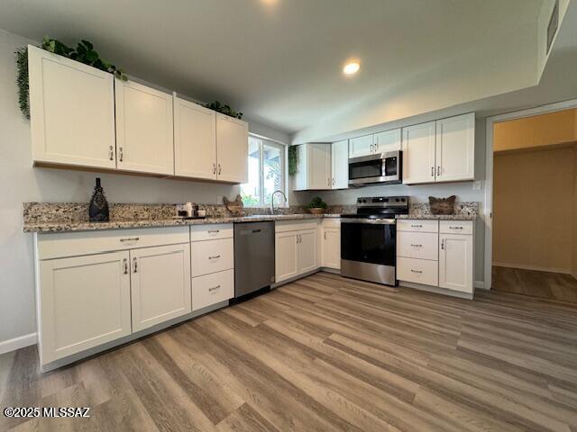 kitchen with stainless steel appliances, light wood-style flooring, and white cabinetry