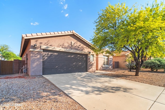 view of front of home featuring a tile roof, concrete driveway, an attached garage, fence, and stucco siding
