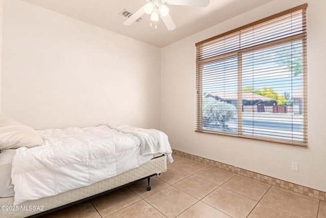 bedroom featuring a ceiling fan, baseboards, multiple windows, and light tile patterned floors