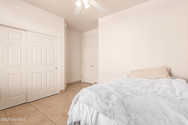 bedroom with a closet, a ceiling fan, baseboards, and light tile patterned floors