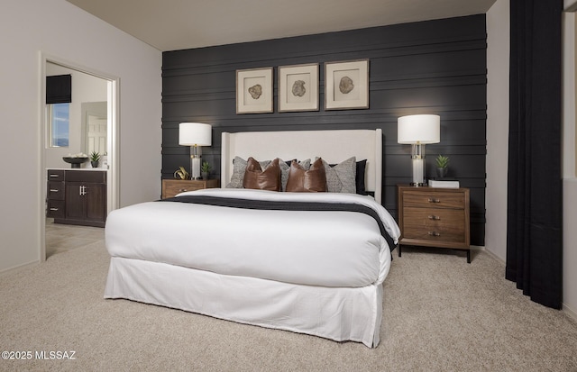 carpeted bedroom with baseboards, ensuite bath, and a decorative wall