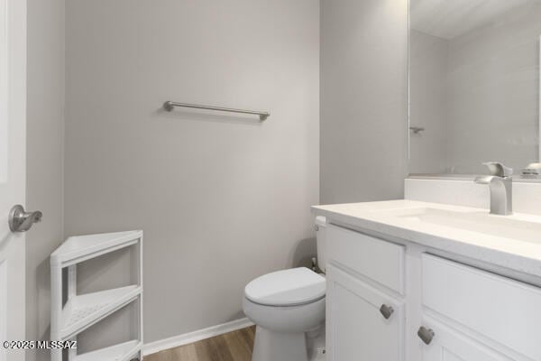 bathroom featuring vanity, baseboards, toilet, and wood finished floors