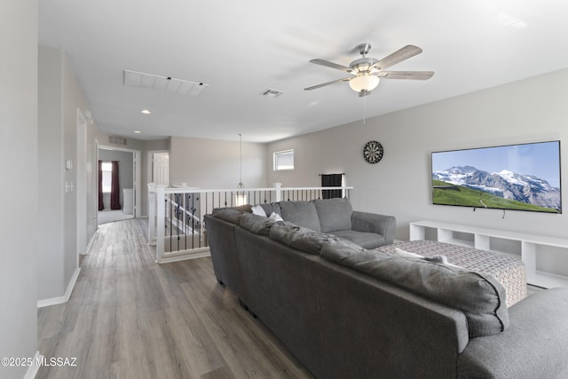 living area with visible vents, a ceiling fan, baseboards, and wood finished floors