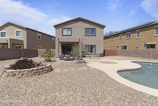 back of house with a fenced in pool, a fenced backyard, a patio area, and stucco siding
