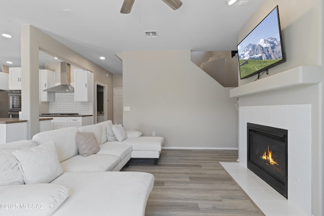 living room with visible vents, ceiling fan, recessed lighting, light wood-type flooring, and a fireplace with flush hearth
