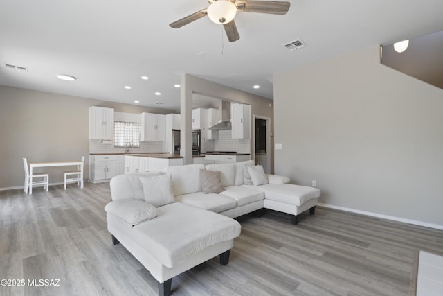 living area featuring ceiling fan, visible vents, and light wood-style floors