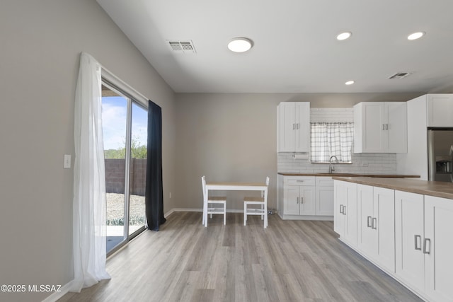 kitchen featuring stainless steel refrigerator with ice dispenser, visible vents, wooden counters, and light wood-type flooring