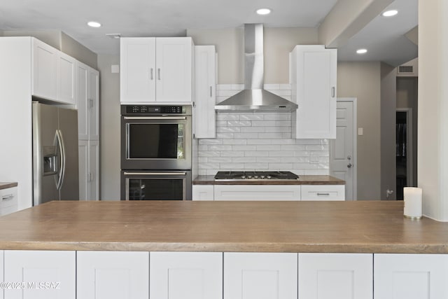 kitchen featuring visible vents, recessed lighting, wall chimney exhaust hood, white cabinets, and stainless steel appliances