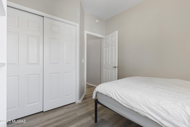 bedroom with baseboards, a closet, and wood finished floors