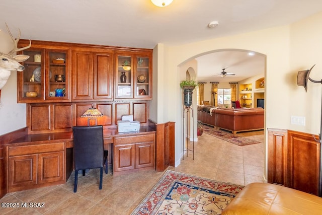61867 E Ironwood Ln, Tucson, AZ 85739 - office space with a ceiling fan, light tile patterned flooring, built in desk, a wainscoted wall, and arched walkways