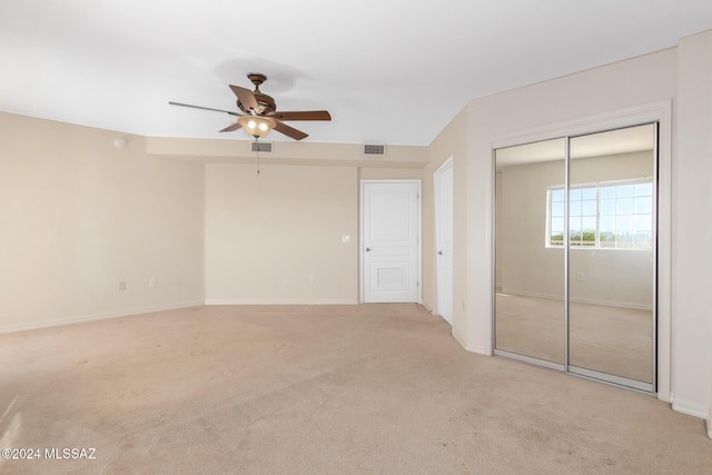 interior space featuring visible vents, ceiling fan, light colored carpet, and baseboards